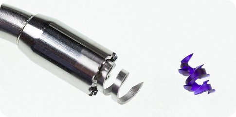 A close-up of a metal dental tool with a spiraled tip next to a small, twisted piece of blue dental material on a white background, showcasing advanced Signum Surgical technology.