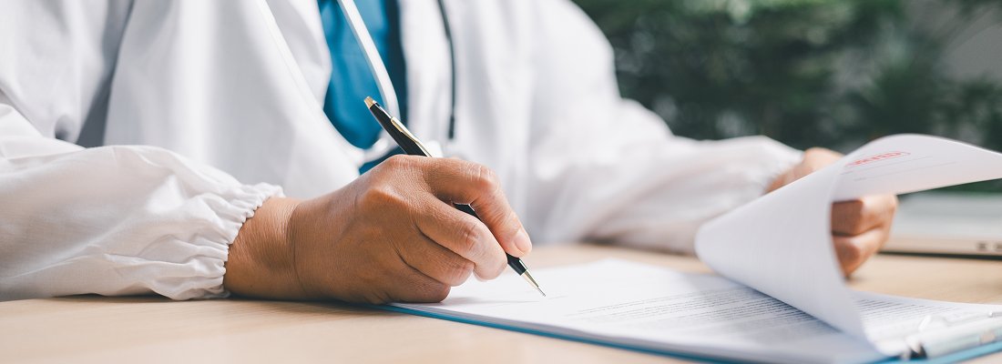 researcher or doctor with a pen in hand writing on a research paper of published outcomes for anal fistula procedures or other type of study